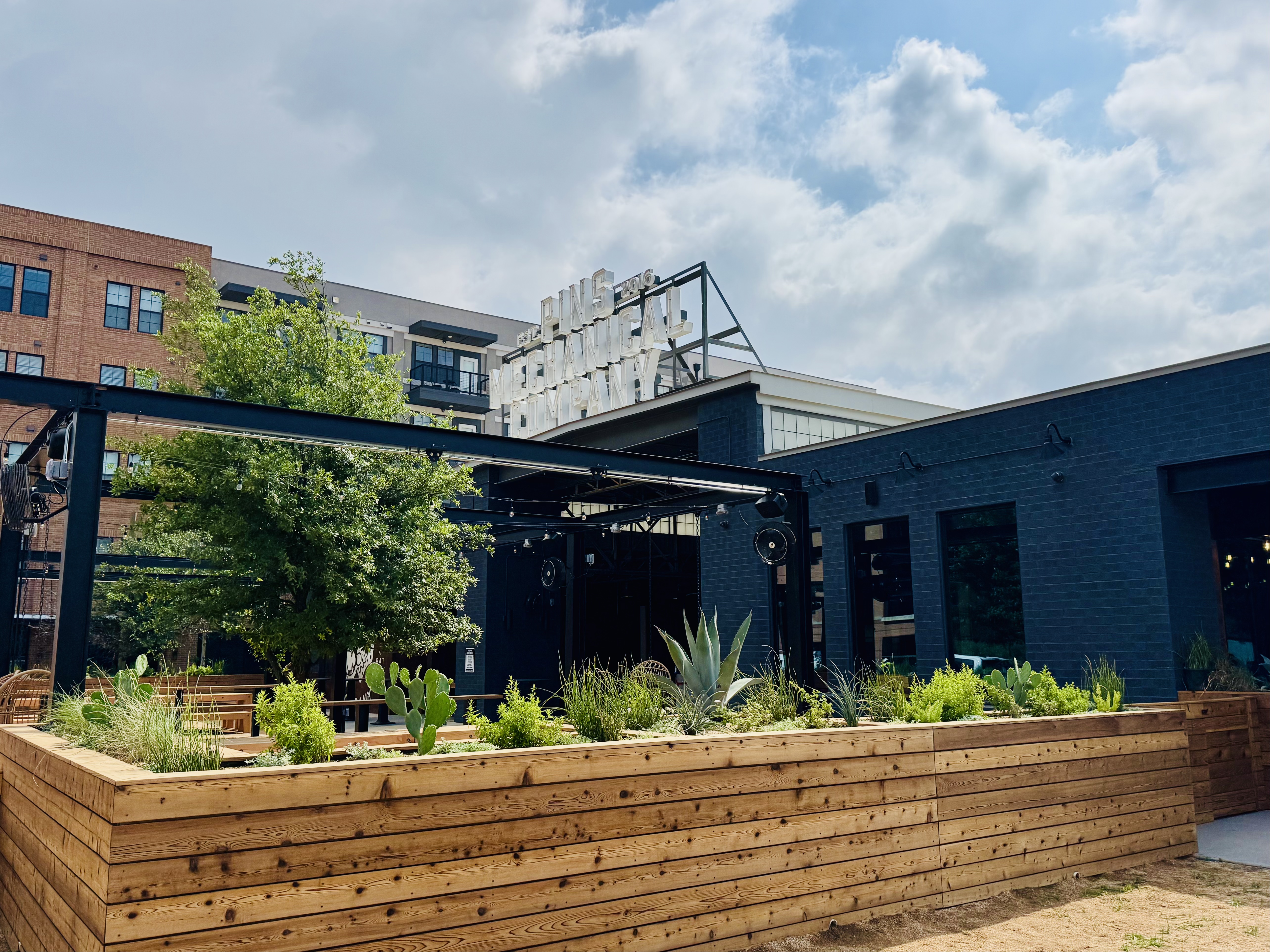 The cedar planter wall running the length of the patio, oak and steel canopy beyond